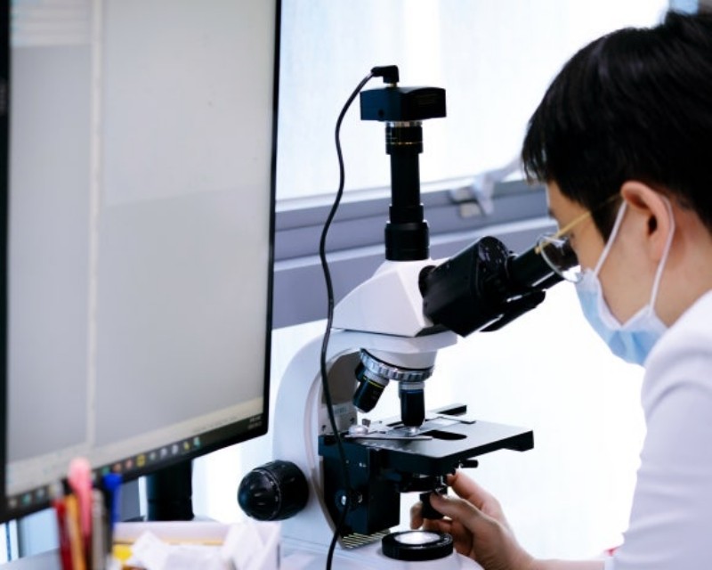 Clinician examining a sample through a microscope