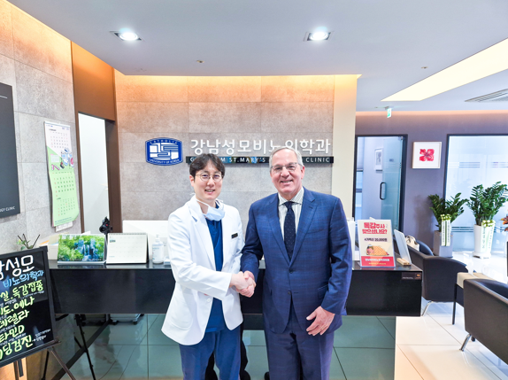 Doctor and visitor shaking hands at the clinic reception desk