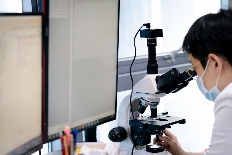 Clinician examining a sample through a microscope
